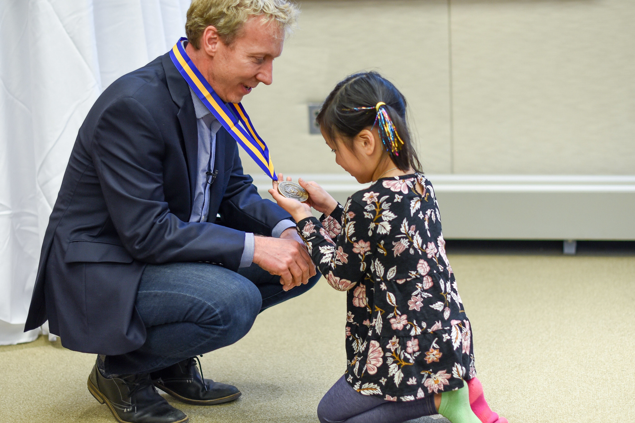 Blaauw kneels so a little girl can inspect his medal