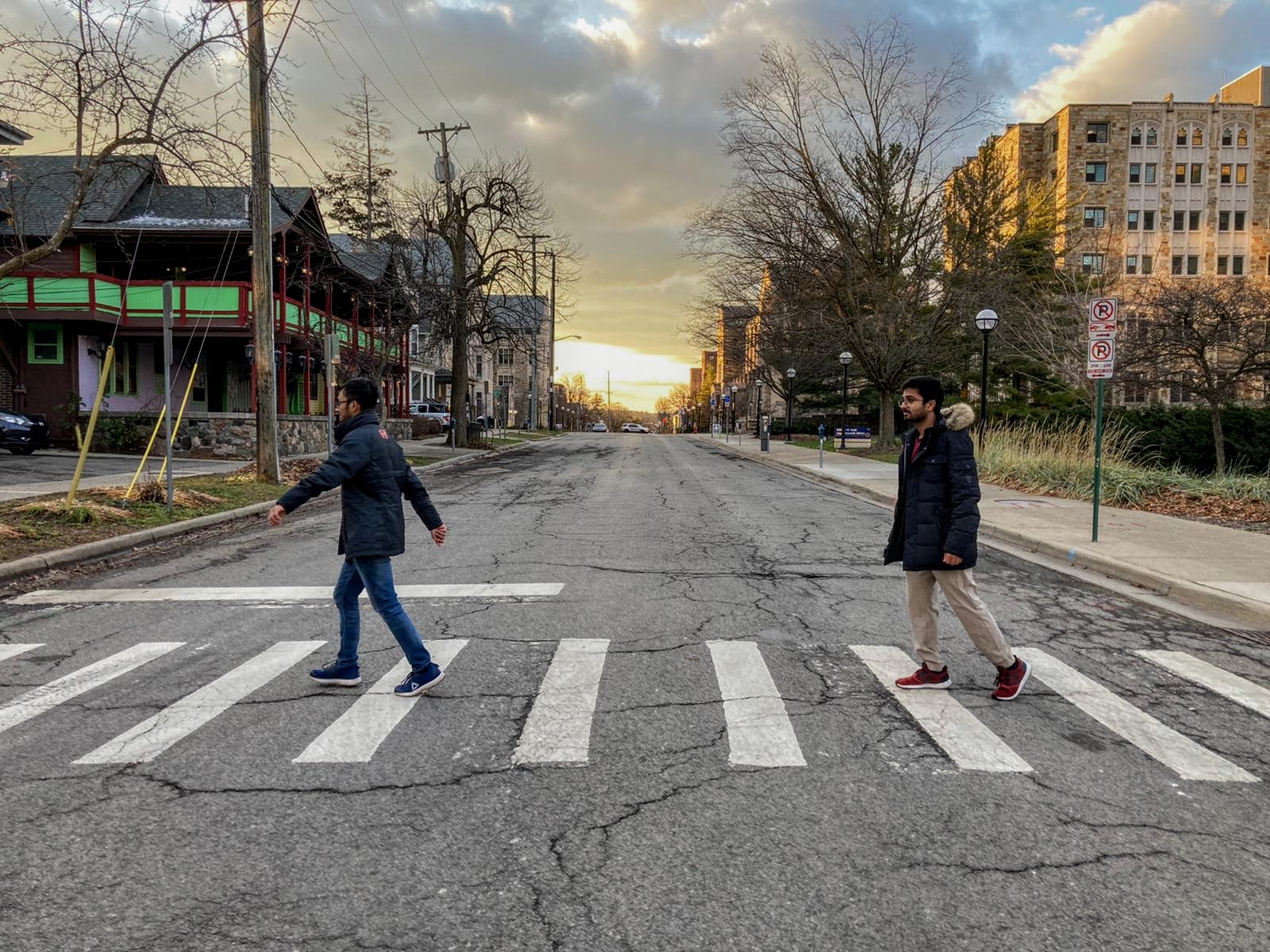 two students walk in a crosswalk mimicking Abbey Road album cover